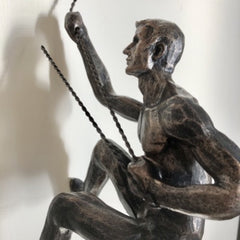 A antique bronze climbing man wall sculpture with twist wire cord and loop for easy hanging